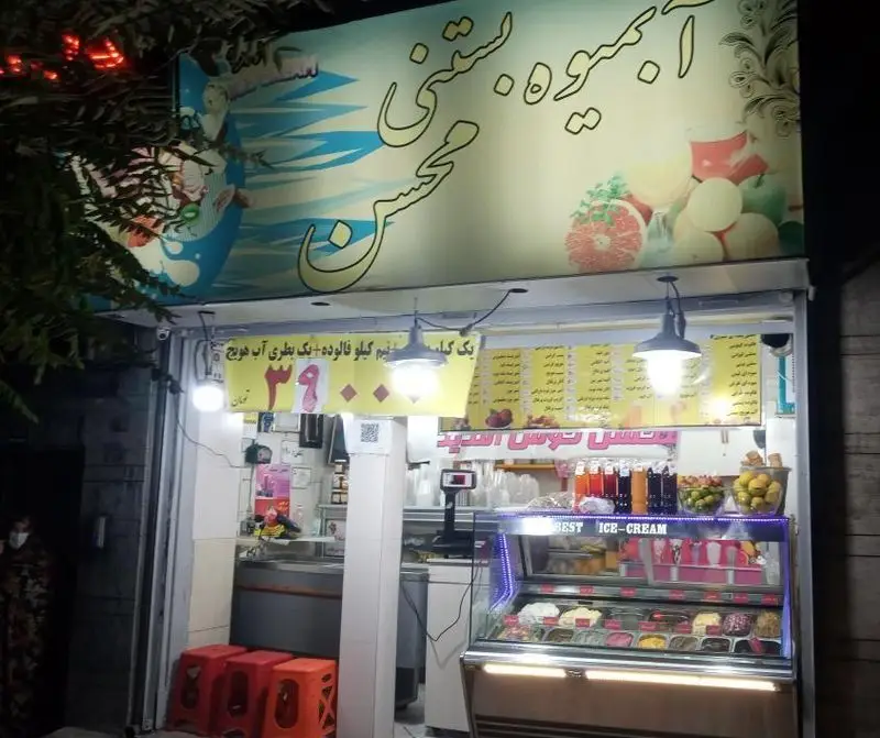 تصویر فروشگاه آبمیوه و فالوده بستنی محسن۲ در شب، با ویترین پر از بستنی‌های متنوع و آبمیوه‌های تازه و خوش طعم.