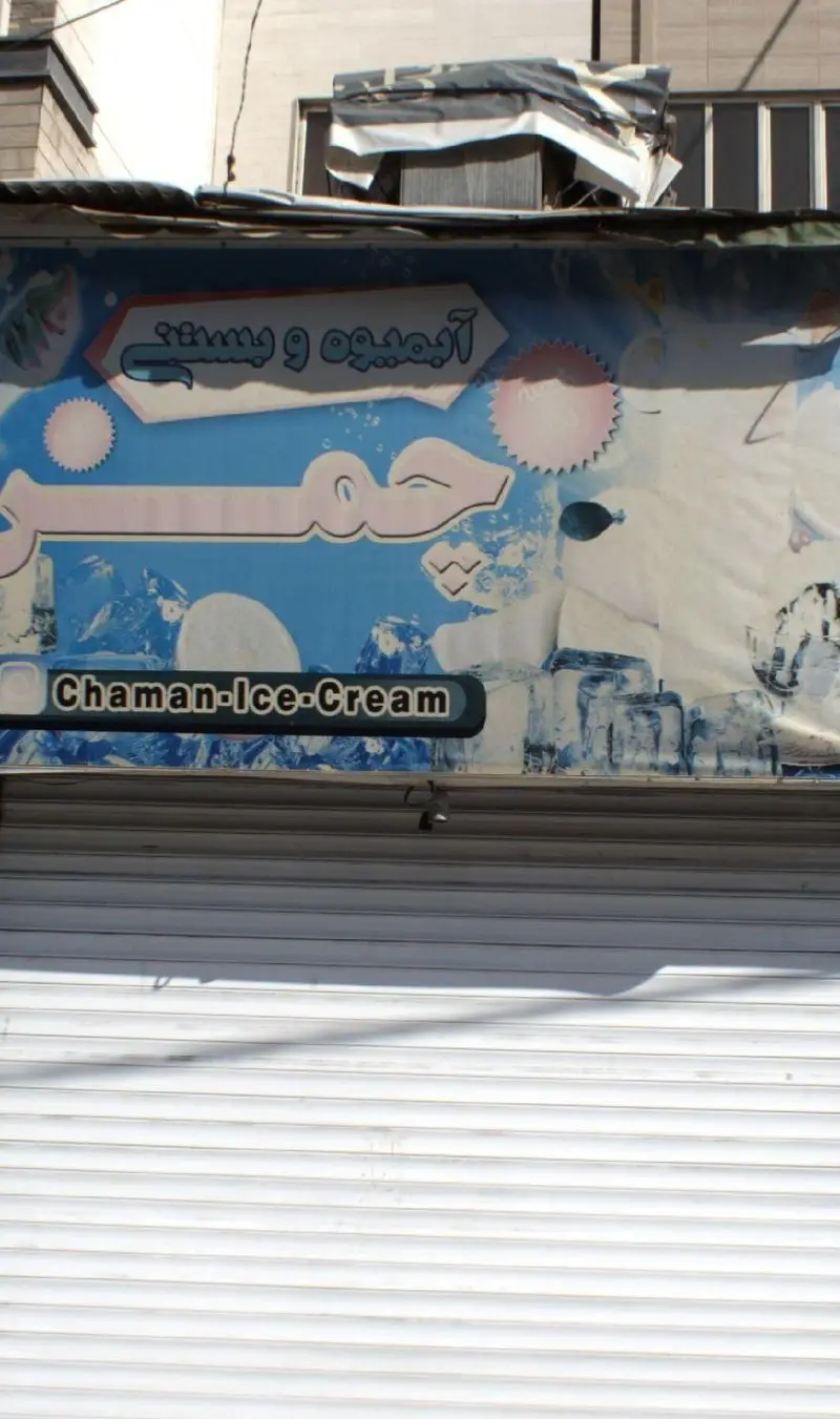 تابلو و کرکره بسته مغازه آبمیوه و بستنی چمن، با لوگوی فارسی و انگلیسی، آماده ارائه محصولات خنک.