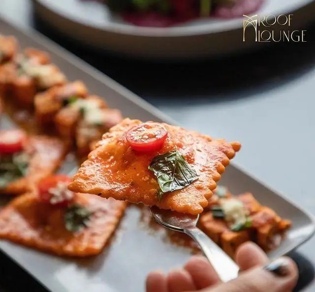 تصویری از راویولی‌های خوشرنگ با سس گوجه و ریحان در کافه رستوران روف لانژ. طعمی بی‌نظیر برای دوستداران غذای ایتالیایی.