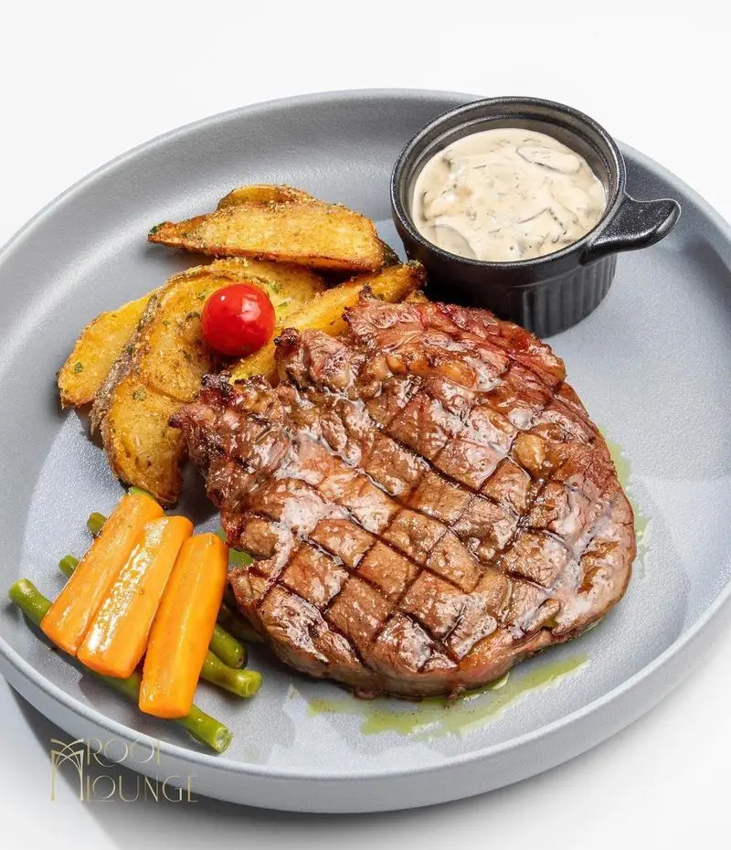 استیک گریل آبدار، همراه با سس خامه ای قارچ، وج سیب زمینی، هویج و لوبیا سبز در کافه رستوران روف لانژ.