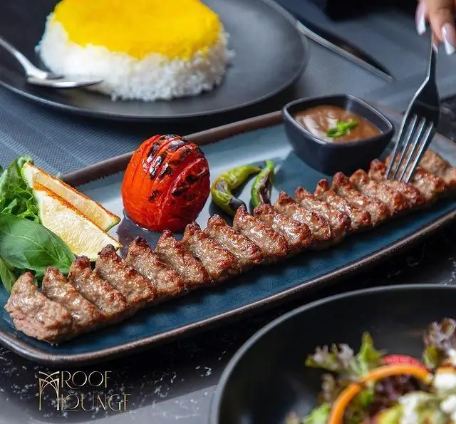 کباب کوبیده لذیذ با برنج زعفرانی، گوجه کبابی و فلفل در کافه رستوران روف لانژ؛ تجربه‌ای دلپذیر از غذای ایرانی.