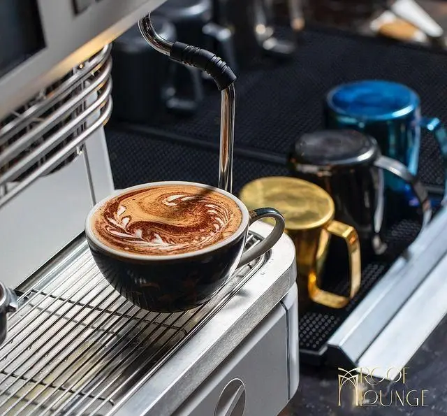نمایی نزدیک از یک فنجان قهوه با لاته آرت هنرمندانه روی دستگاه اسپرسوساز در کافه رستوران روف لانژ. طعم بی‌نظیر.