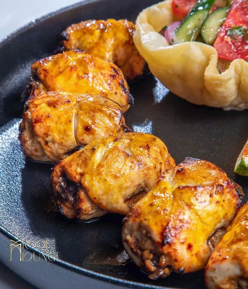 کباب مرغ گریل شده طلایی و آبدار در کنار سالاد تازه با گوجه و خیار، سرو شده در کافه رستوران روف لانژ.