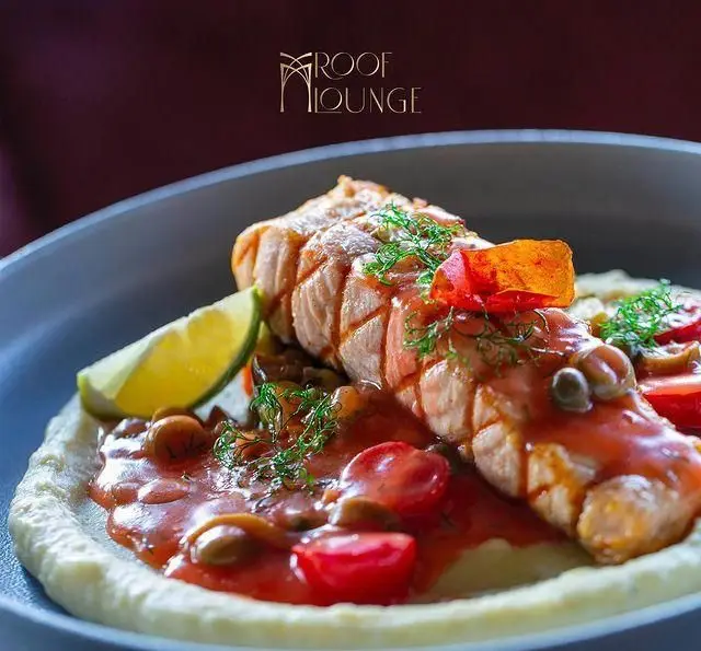 بشقاب زیبای ماهی سالمون ترد با سس گوجه، قارچ، گوجه گیلاسی، کیپر، پوره خامه‌ای و لیمو تازه در کافه رستوران روف لانژ.