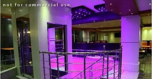 فضای داخلی مدرن و شیک فست فود شایلی با نورپردازی بنفش خیره‌کننده، راه پله استیل و چیدمان جذاب میز و صندلی‌ها.