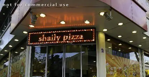 نمای بیرونی جذاب فست فود شایلی با تابلوی پیتزا شایلی روشن در شب، مکانی عالی برای تجربه طعم بی‌نظیر.