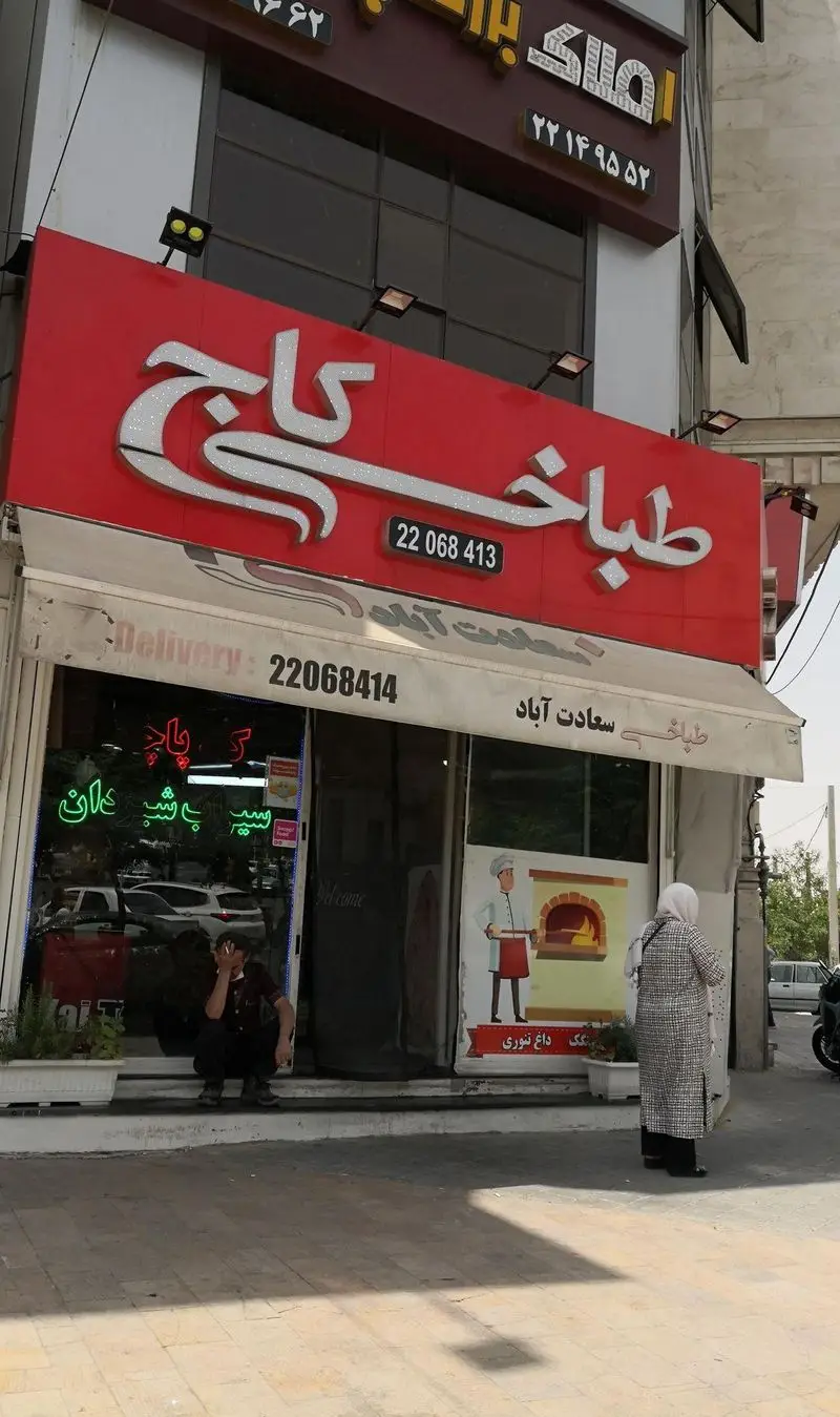 طباخی کاج سعادت آباد با تابلوی قرمز براق، شماره تلفن سفارش کله پاچه و تحویل غذا، و نان داغ سنتی تنوری در محل.