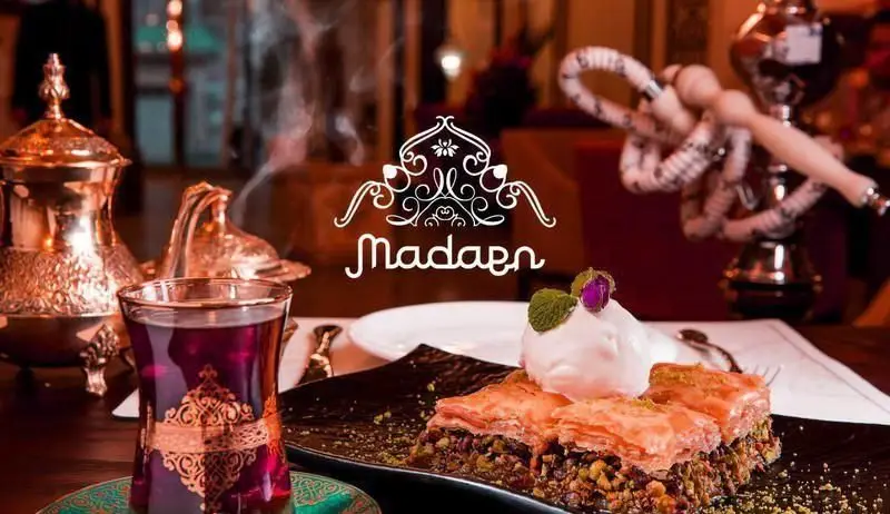 تصویری از کافه رستوران عربی مدائن، شامل باقلوا با بستنی، چای اصیل و قلیان، نشان‌دهنده فضای دلنشین و سنتی.