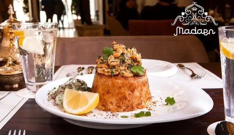 میگو پلو لذیذ با ته‌دیگ رشته‌ای سرو شده در کافه رستوران عربی مدائن، همراه با نوشیدنی در فضایی دلنشین و دکوراسیون سنتی.