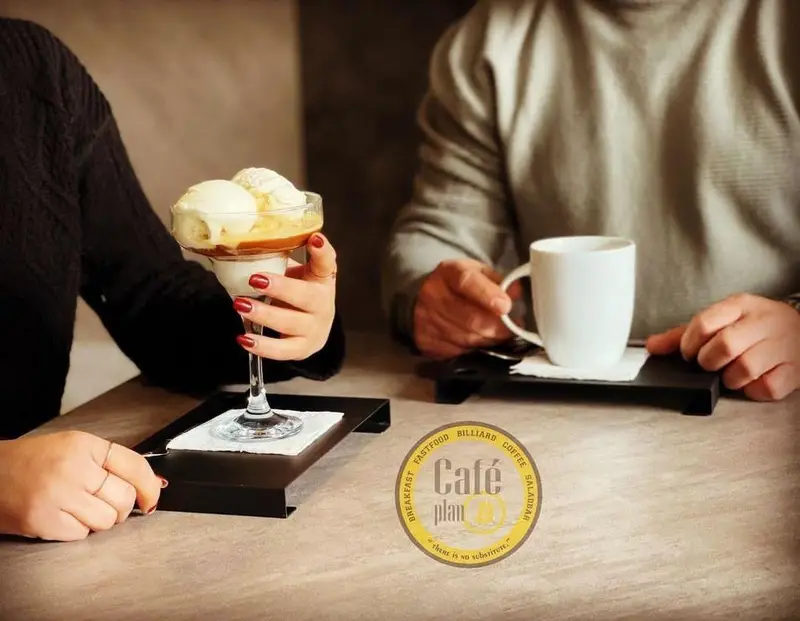 دو مشتری در کافه بیلیارد پلن بی از قهوه و دسر بستنی مخصوص لذت می‌برند. بهترین تجربه نوشیدنی و محیطی دلنشین در کافه.
