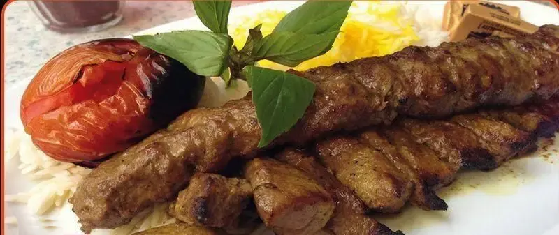 کباب اصیل ایرانی شامل کوبیده و چنجه به همراه چلو سفید زعفرانی، گوجه کبابی و سبزی تازه از تهیه غذای علی بابا.