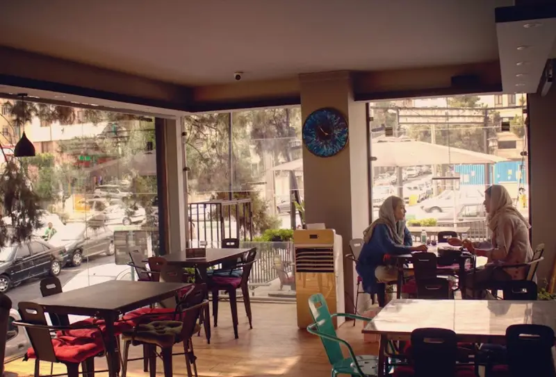 دو خانم در حال گفتگو در فضای دلنشین کافه سالیز، محیطی شیک با نور طبیعی و چشم‌انداز خیابان، ایده‌آل برای قرارهای دوستانه