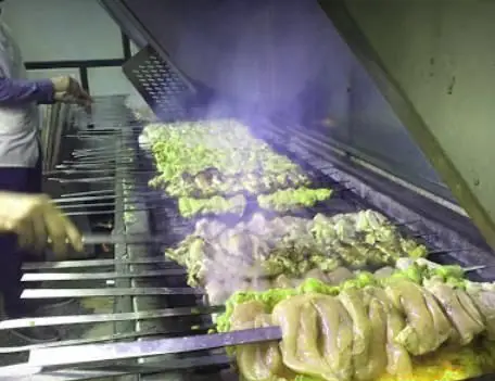 فضای پرحرارت آشپزخانه رستوران محمد: آشپز ماهر در حال گریل کردن تعداد زیادی سیخ جوجه کباب تازه و خوش‌رنگ برای مشتریان.