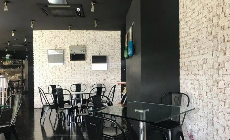 نمای داخلی رستوران باروژ با طراحی صنعتی مدرن، دیوارهای آجری سفید، سقف تیره و چیدمان میز و صندلی‌های مشکی شیک.