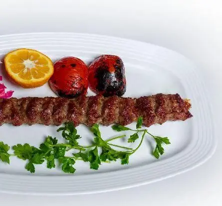 کباب کوبیده لذیذ کبابخانه دوزلی (شعبه صادقیه) با گوجه کبابی، نارنج تازه و سبزیجات، یک غذای سنتی و محبوب ایرانی.