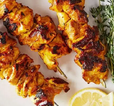 جوجه کباب چوبی گریل شده کبابخانه دوزلی شعبه صادقیه با لیمو و سبزی تازه، غذایی خوشمزه و اصیل ایرانی.