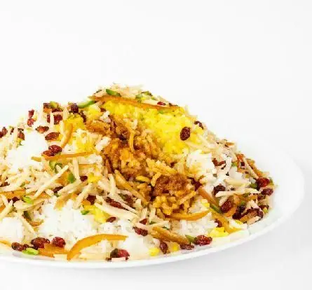 بشقابی پر از زرشک پلو زعفرانی مجلسی، تزئین شده با زرشک، خلال پرتقال و مغز پسته، از بهترین غذاهای کبابخانه دوزلی صادقیه.