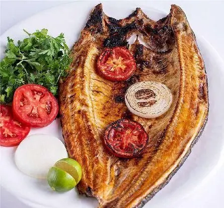 ماهی کبابی لذیذ و تازه با سبزیجات، گوجه، پیاز و لیمو، انتخابی سالم از منوی کبابخانه دوزلی شعبه صادقیه تهران.