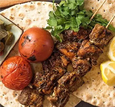 کباب لذیذ جوجه یا برگ به همراه گوجه کبابی، نان داغ و مخلفات در کبابخانه دوزلی شعبه صادقیه، غذای سنتی و خوشمزه ایرانی.