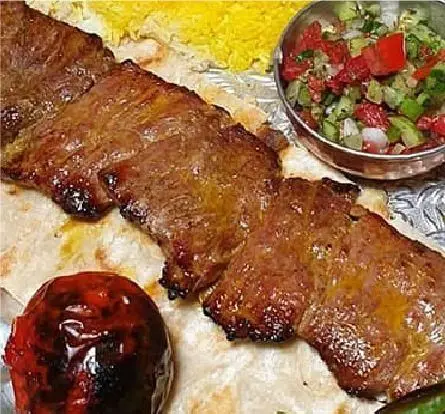 تصویری از چلوکباب برگ لذیذ کبابخانه دوزلی شعبه صادقیه تهران با دورچین کامل شامل برنج زعفرانی، سالاد و گوجه کبابی