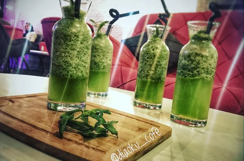 چهار نوشیدنی سبز خنک و تازه اسموتی نعنایی کافه دیاکو، با تزئین برگ نعنا روی تخته چوبی، مناسب برای لحظاتی دلنشین.