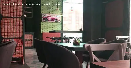 دکوراسیون داخلی رستوران ایتالیایی ای تی اف، با دیوار آجری سبز، تابلو ماشین کلاسیک و محیطی دنج و مدرن برای پذیرایی.