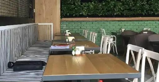 نمایی از فضای داخلی رستوران ایتالیایی ای تی اف با میزهای چوبی، صندلی‌های سفید و نشیمن‌های راه راه، آماده پذیرایی از مهمانان.