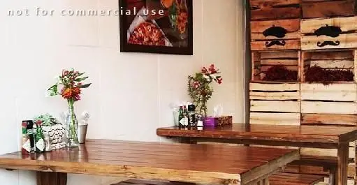 دکوراسیون داخلی فست فود آوان با میزهای چوبی زیبا، قفسه‌های دیواری طرح سبیل و گل‌های طبیعی، محیطی دلنشین برای مشتریان.