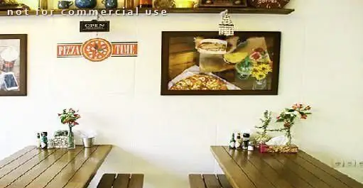 نمای داخلی فست فود آوان با میزهای چوبی روستیک، تزئینات پیتزا تایم و تابلوهای هنری غذا، فضایی دلپذیر برای مشتریان.