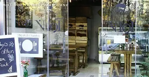 ورودی و دکوراسیون داخلی فست فود آوان. تابلوی سیاه پیشنهادات روز شامل پیتزا و استیک، میز و نیمکت‌های چوبی، فضایی گرم و دلنشین.