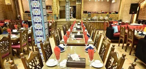 فضای داخلی وسیع و زیبای سفره خانه سنتی باران با دکوراسیون اصیل ایرانی، میز و صندلی های چوبی آماده پذیرایی از میهمانان در محیطی گرم.