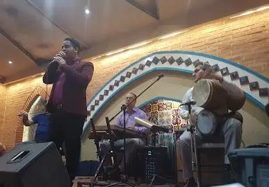 خواننده و نوازندگان در حال اجرای موسیقی زنده سنتی در سفره خانه سنتی باران، فضایی دلنشین و اصیل ایرانی.