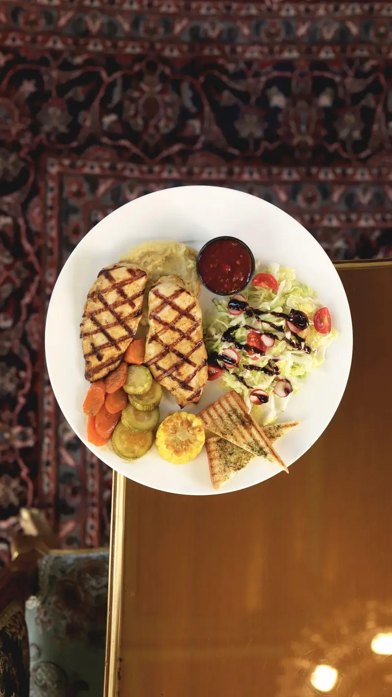 سینه مرغ گریل همراه با پوره سیب‌زمینی، سبزیجات تازه، سالاد و نان سیر در کافه‌حیات هزار افسانْ. تجربه‌ای لذیذ از غذاهای ما.