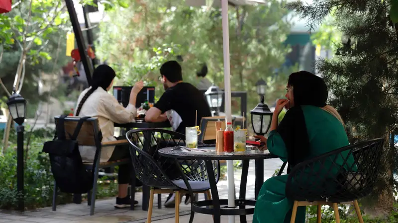 دورهمی در فضای باغ کافه‌حیات هزار افسانْ. مشتریان در حال نوشیدن و لذت از محیط سبز و آرامش‌بخش کافه.