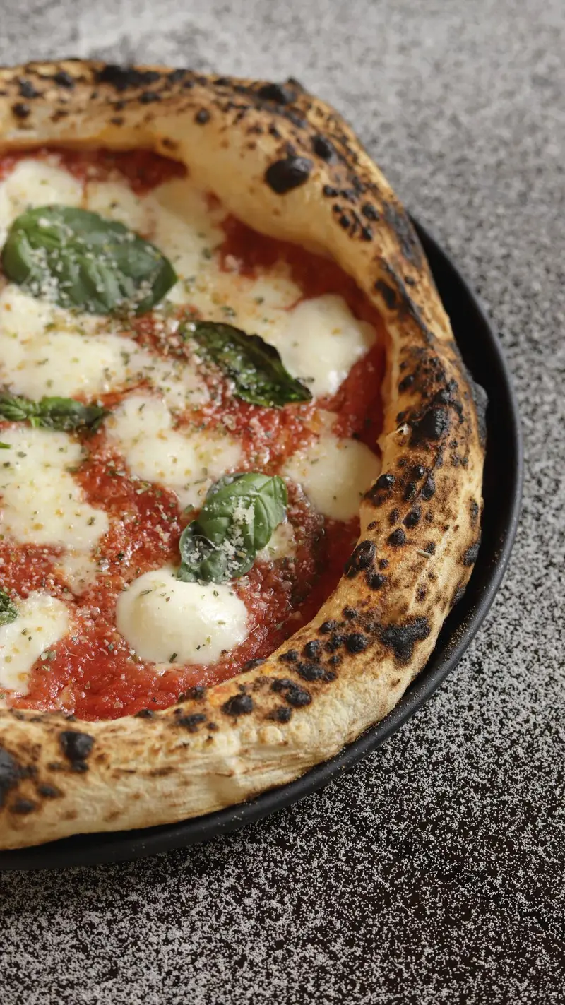پیتزای لذیذ ناپولیتن با خمیر ترد و پفکی، سس گوجه فرنگی، پنیر موزارلا و برگ‌های تازه ریحان در کافه‌حیات هزار افسان.