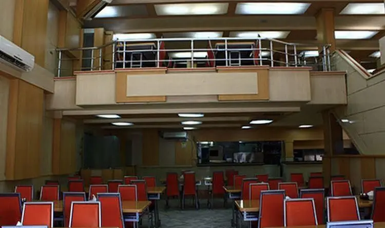 رستوران جوان هنرور۱: نمایی از سالن غذاخوری بزرگ و منظم، شامل طبقه همکف و نیم‌طبقه، با میز و صندلی‌های راحت و دکوراسیون چوبی.