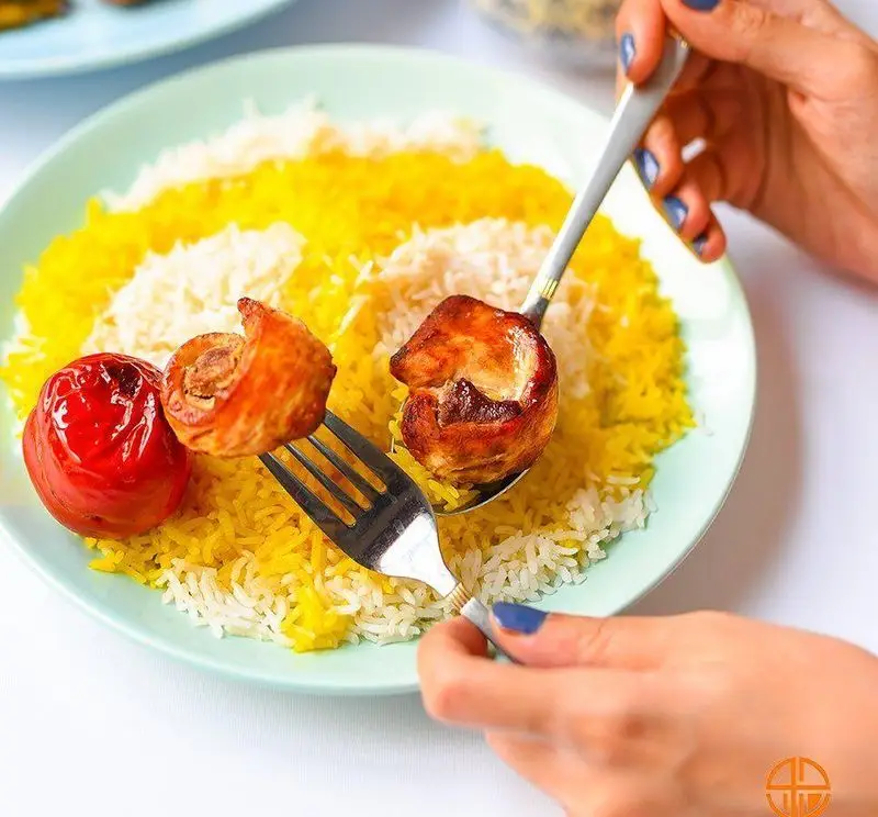 یک پرس چلو مرغ زعفرانی و سفید از رستوران جوان هنرور۱ با تکه‌های مرغ برشته و گوجه کبابی، یک غذای اصیل و خوشمزه ایرانی.