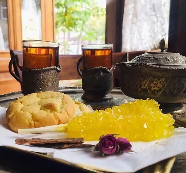 تجربه دلپذیر عمارت نیلی: سرو چای اصیل ایرانی با نبات زعفرانی، شیرینی سنتی، دارچین و غنچه گل محمدی در فضایی دلنشین.