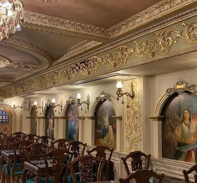 فضای داخلی لوکس و سنتی رستوران نقش جهان با دکوراسیون طلایی، سقف‌های حکاکی شده، نقاشی‌های دیواری و مبلمان چوبی زیبا.