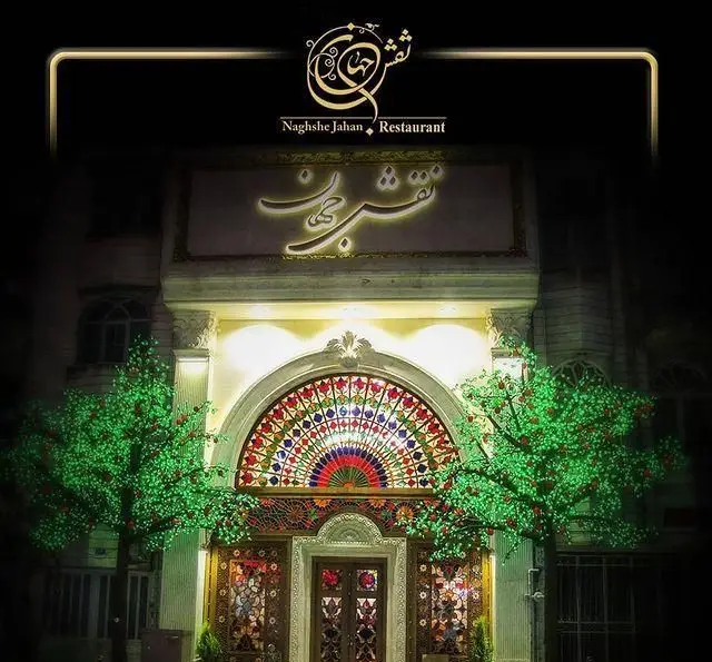 تصویری جذاب از نمای شبانه رستوران نقش جهان. ورودی زیبا با نورپردازی گرم، شیشه‌های رنگی و المان‌های معماری سنتی چشم‌نواز.