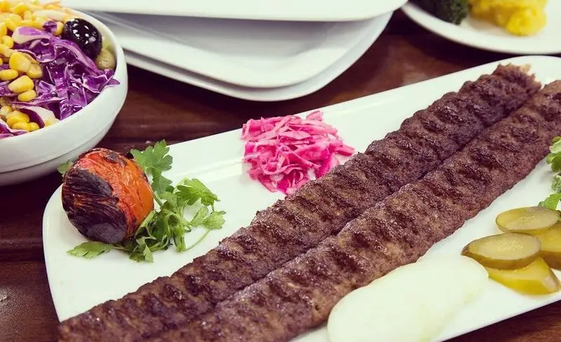 کباب کوبیده لذیذ باغچه رستوران سنتی صحرا با گوجه کبابی، پیاز، ترشی و سالاد فصل. بهترین غذای ایرانی برای شما.