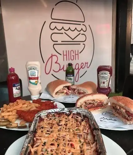 نمایی نزدیک از غذاهای متنوع فست فود های برگر: ساندویچ‌های بزرگ، سیب‌زمینی، مرغ سوخاری و ظرف گراتن پنیر، به همراه سس‌ها.