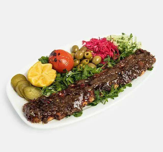 غذای سنتی رستوران آفاق: کباب ترش لذیذ با سس رب انار، همراه گوجه کبابی، لیمو، زیتون، خیارشور و سبزیجات تازه. تجربه طعم اصیل.