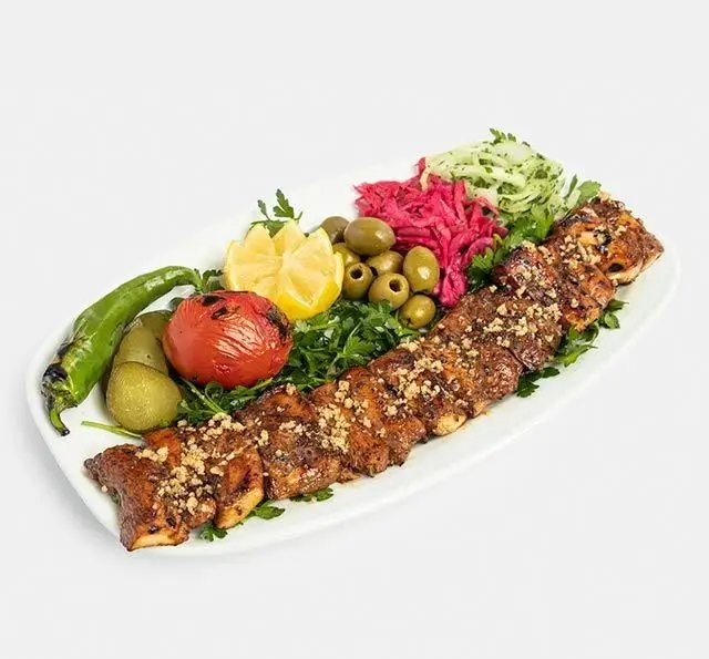 بشقاب کباب مرغ مخصوص رستوران سنتی آفاق، با تزئین گوجه، فلفل، زیتون، لیمو، ترشی، سبزیجات و آجیل روی کباب.