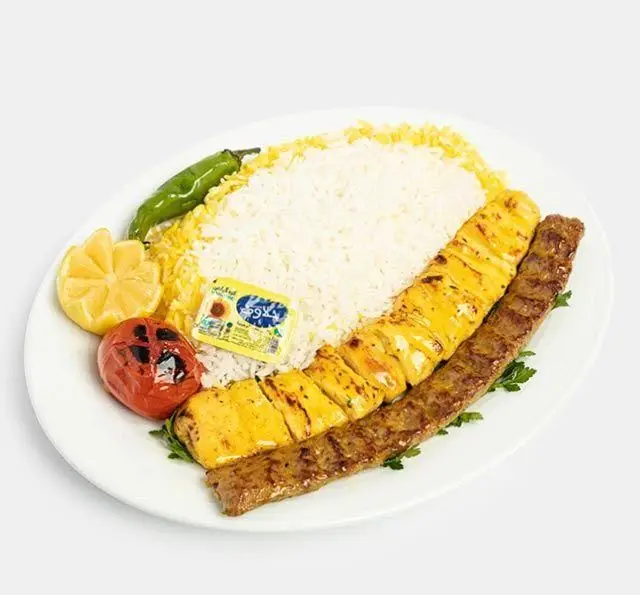 چلو کباب کوبیده و جوجه کباب لذیذ رستوران سنتی آفاق با برنج زعفرانی، کره، گوجه و فلفل کبابی. غذای سنتی ایرانی.