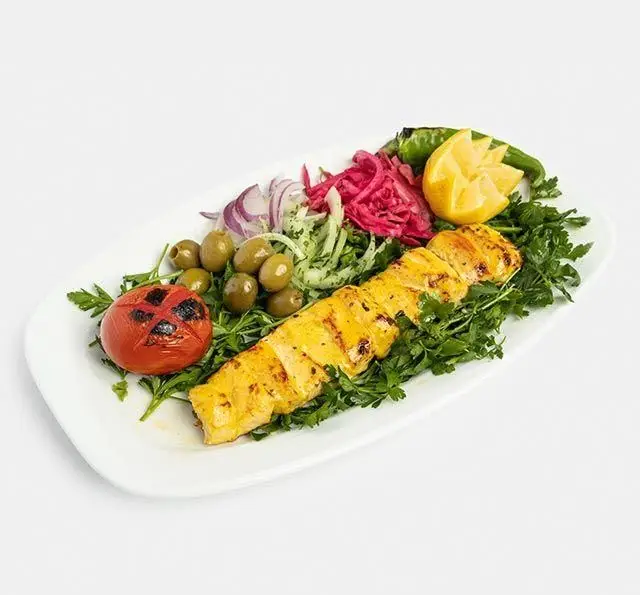 جوجه کباب لذیذ رستوران سنتی آفاق با مخلفات تازه شامل گوجه کبابی، زیتون، سبزی و پیاز. طعم اصیل غذای ایرانی.