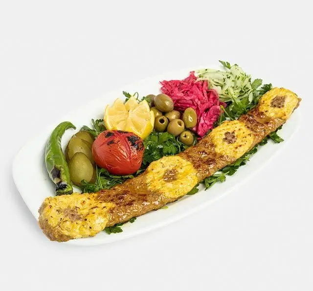 کباب برگ مخصوص رستوران سنتی آفاق با زرده تخم مرغ، همراه با دورچین کامل شامل زیتون، گوجه، فلفل، ترشی و سبزیجات تازه.