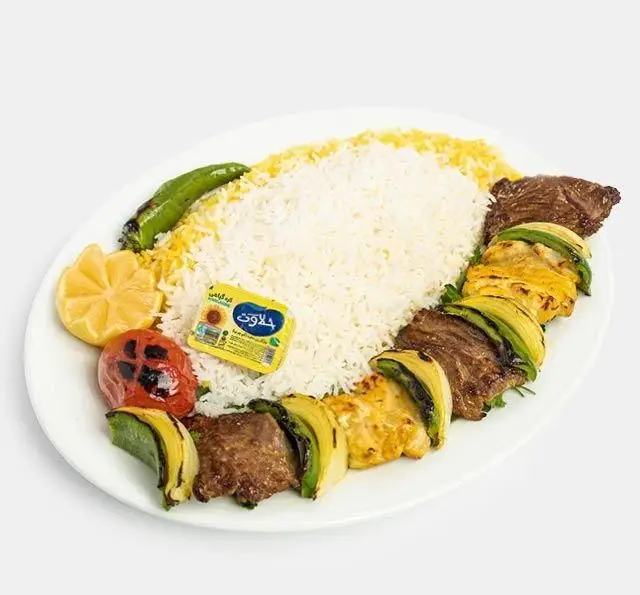 چلو کباب میکس لذیذ رستوران سنتی آفاق شامل کباب گوشت و جوجه کباب با پیاز و فلفل کبابی، برنج زعفرانی، کره، گوجه و لیمو.