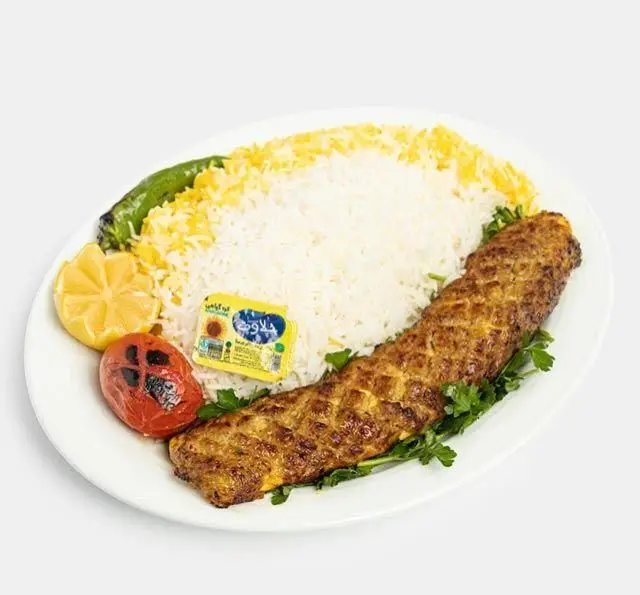 کباب کوبیده لذیذ ایرانی با پلو زعفرانی، گوجه کبابی، فلفل، لیمو و کره، غذای محبوب رستوران سنتی آفاق.