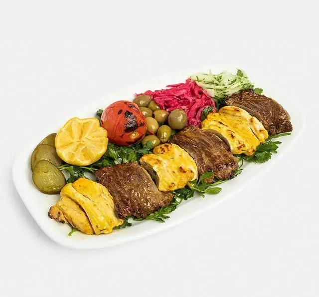 بشقاب کباب مخلوط از رستوران سنتی آفاق شامل کباب برگ، جوجه کباب، گوجه کبابی، لیمو، زیتون و مخلفات تازه. غذای اصیل ایرانی.